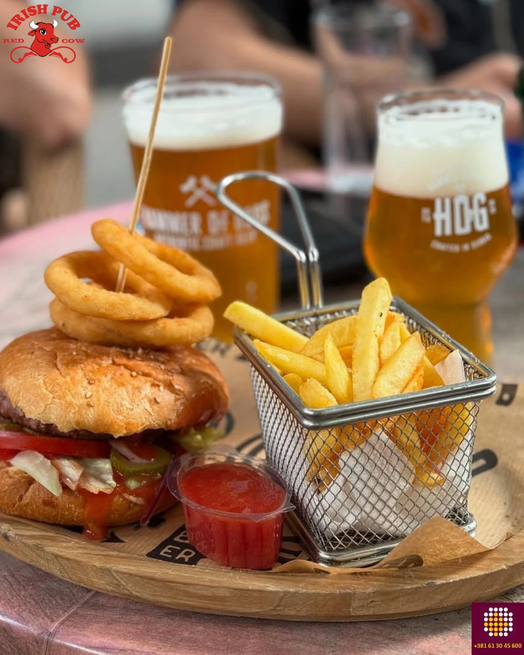 Ljuti burger sa dodacima, uz čašu piva servirano i posluženo na stolu